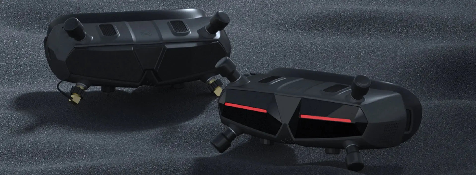 Two black, futuristic HeadphoneHeat WalkSnail Avatar Pro Night Vision Edition HD devices with red lights and multiple sensors are positioned on a textured, dark sandy surface.
