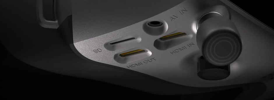 Close-up of the HeadphoneHeat WalkSnail Avatar Pro Night Vision Edition HD, showing SD, HDMI OUT, HDMI IN, and A/V IN ports and a control knob on the right. The metallic finish highlights its advanced FPV goggle features.